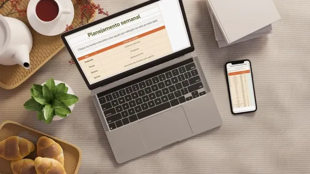 Notebook e celular com a planilha aberta, sobre a mesa